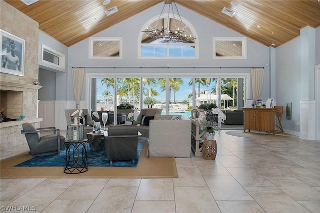 living room with a fireplace, wooden ceiling, a high ceiling, and an inviting chandelier