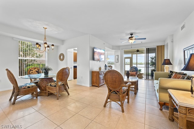 tiled living room with ceiling fan with notable chandelier and a wealth of natural light