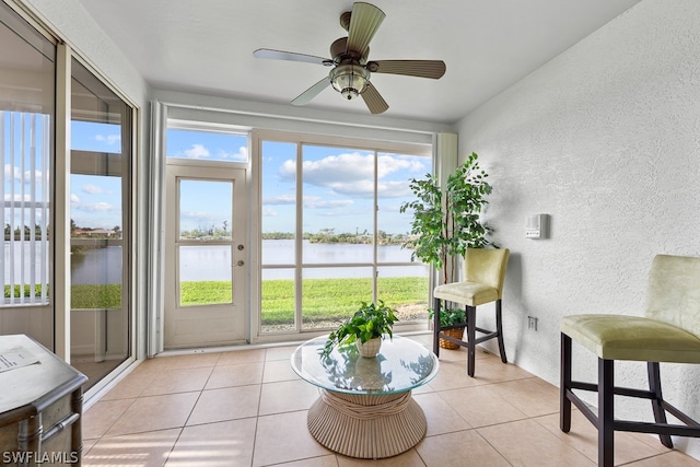 sunroom / solarium with a water view and ceiling fan