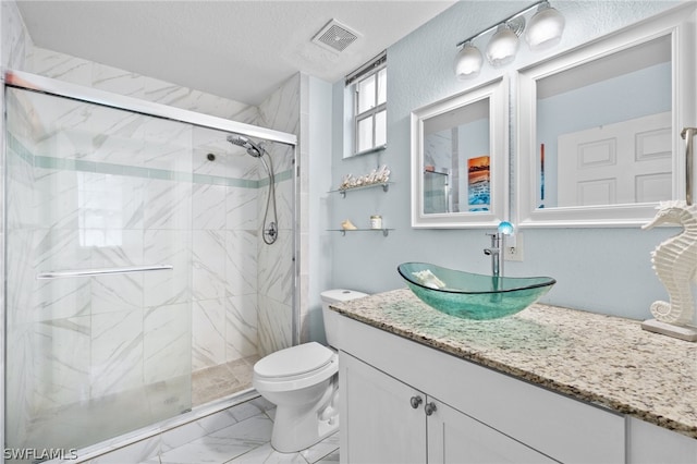 bathroom with a shower with door, vanity, a textured ceiling, and toilet