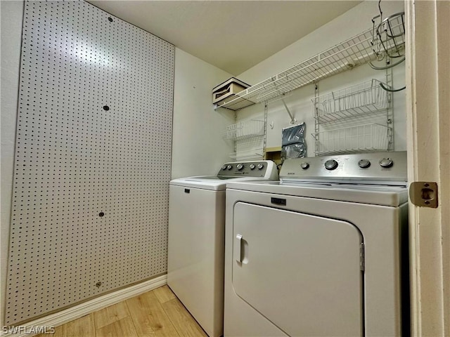 laundry room featuring laundry area, baseboards, separate washer and dryer, and light wood finished floors