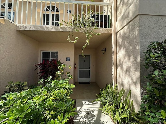 property entrance with a balcony and stucco siding