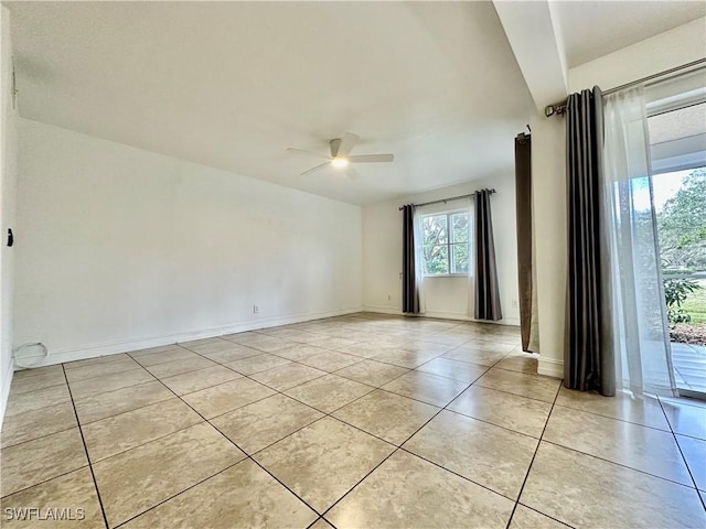 empty room with ceiling fan, baseboards, and light tile patterned floors