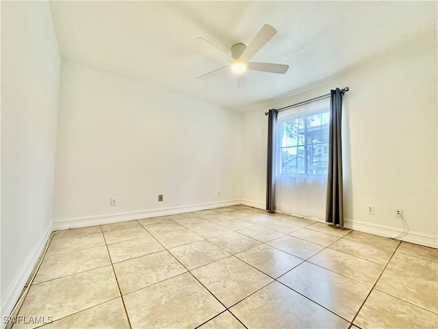 spare room featuring light tile patterned flooring, ceiling fan, and baseboards