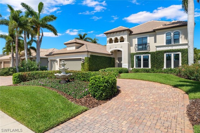 mediterranean / spanish-style home featuring a balcony, a garage, and a front yard