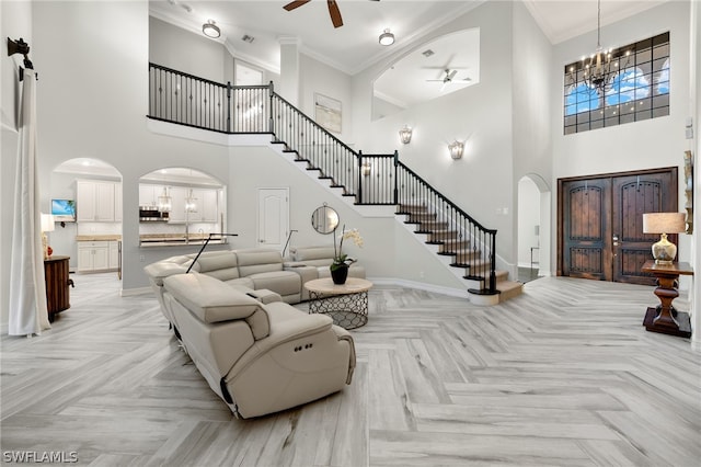 living room with crown molding, a towering ceiling, ceiling fan with notable chandelier, and light parquet floors