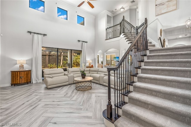 living room featuring crown molding, parquet flooring, ceiling fan, and a high ceiling