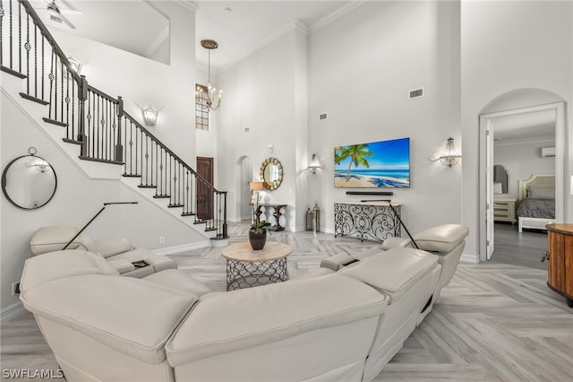 living room featuring a wall mounted air conditioner, a chandelier, light parquet floors, ornamental molding, and a high ceiling