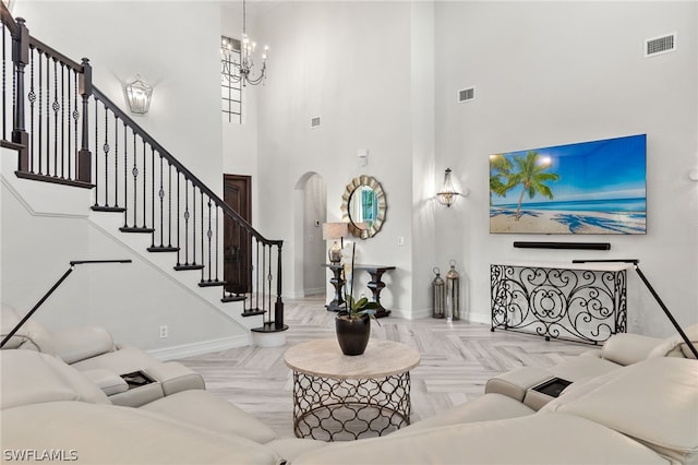 living room with an inviting chandelier, a high ceiling, and light parquet floors