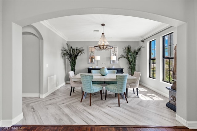 dining space featuring crown molding, light parquet flooring, and a chandelier