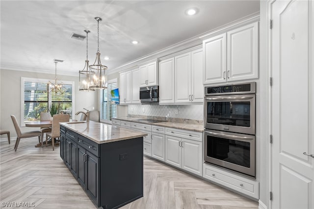 kitchen featuring pendant lighting, white cabinetry, appliances with stainless steel finishes, and a center island with sink