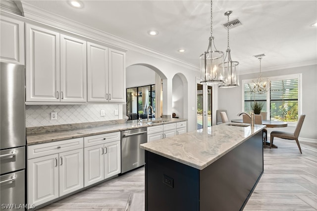 kitchen featuring sink, white cabinetry, stainless steel appliances, an island with sink, and decorative light fixtures