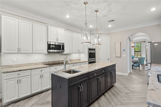 kitchen with sink, decorative light fixtures, a center island with sink, appliances with stainless steel finishes, and white cabinets