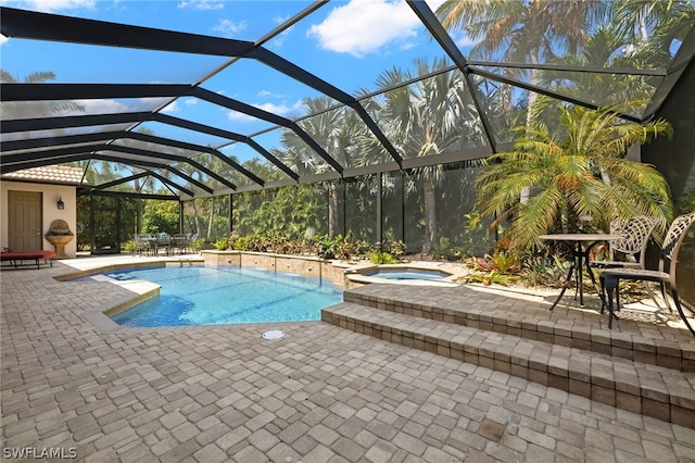 view of pool with a patio area, an in ground hot tub, and glass enclosure