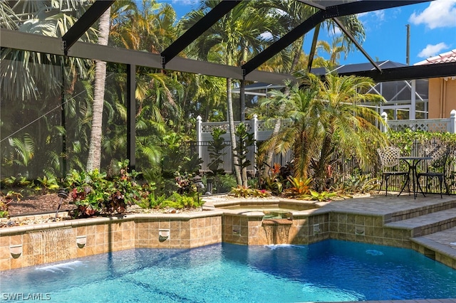 view of pool featuring an in ground hot tub, pool water feature, a patio, and glass enclosure