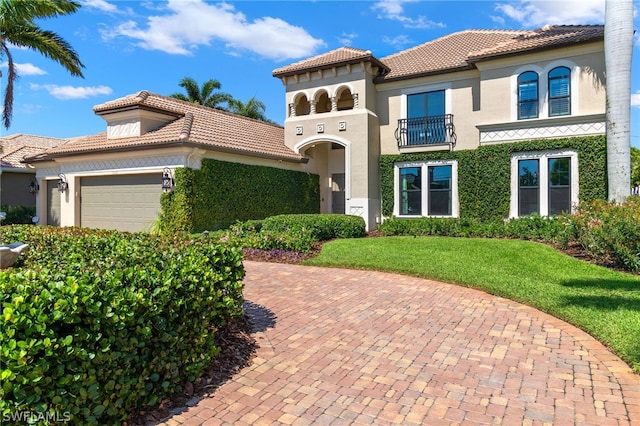 mediterranean / spanish-style house with a garage, a balcony, and a front yard