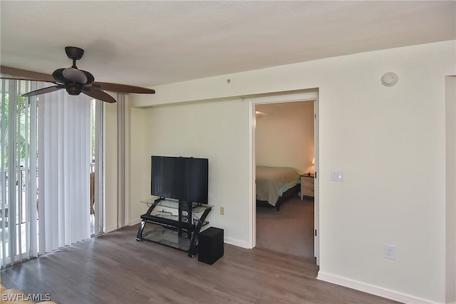 living room featuring ceiling fan and dark wood-type flooring