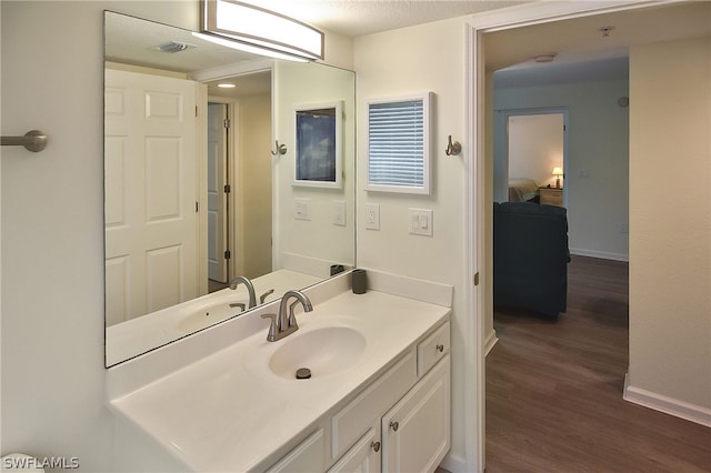 bathroom with wood-type flooring, vanity, and a textured ceiling