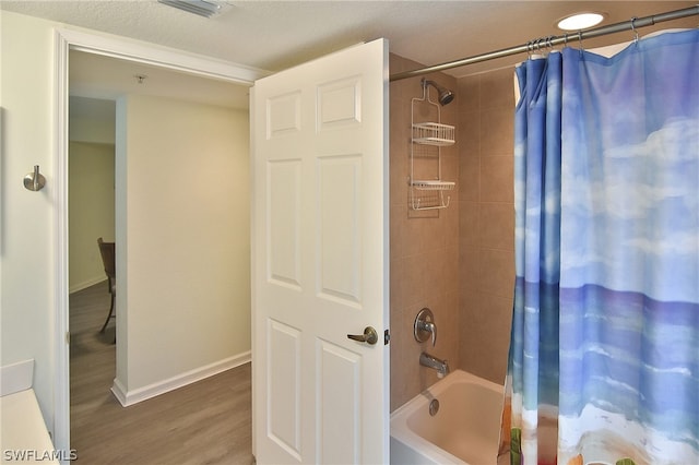 bathroom with hardwood / wood-style floors and shower / tub combo with curtain