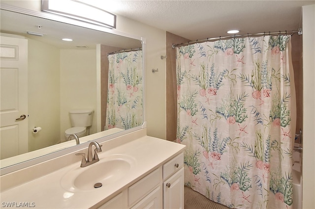 bathroom with vanity, toilet, and a textured ceiling