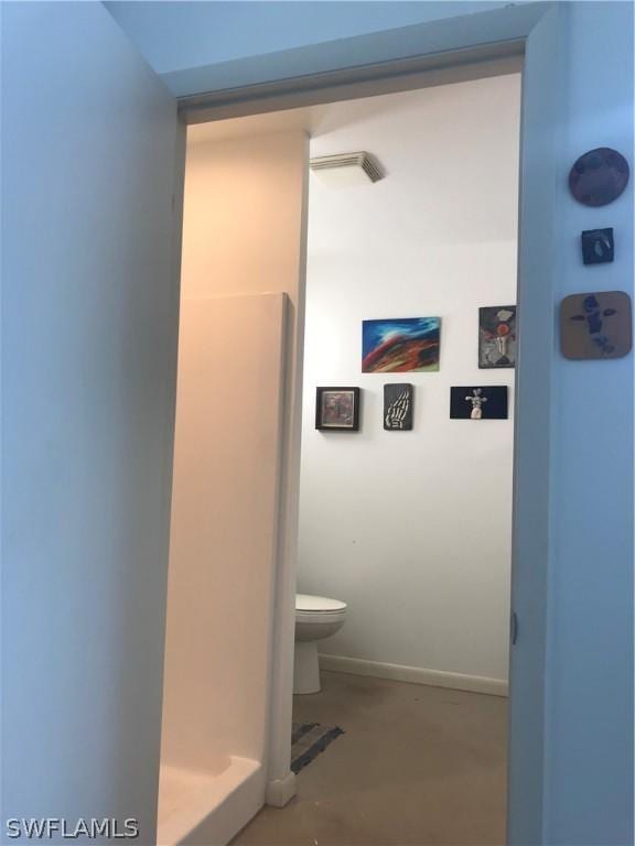 bathroom with concrete flooring and toilet