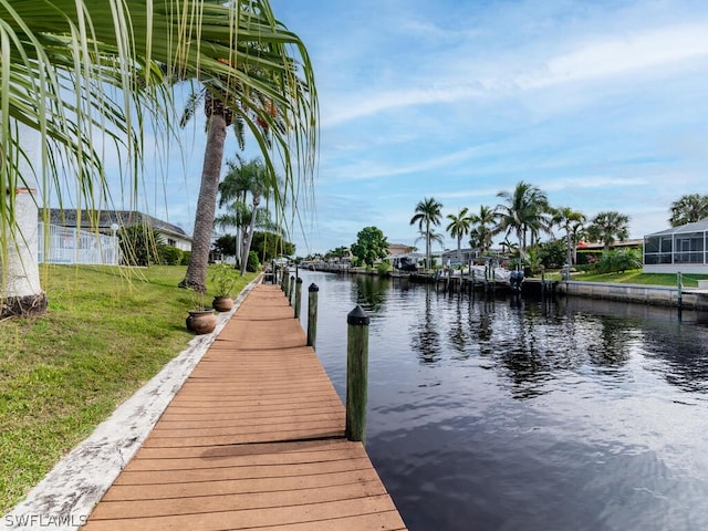 view of dock with a lawn and a water view