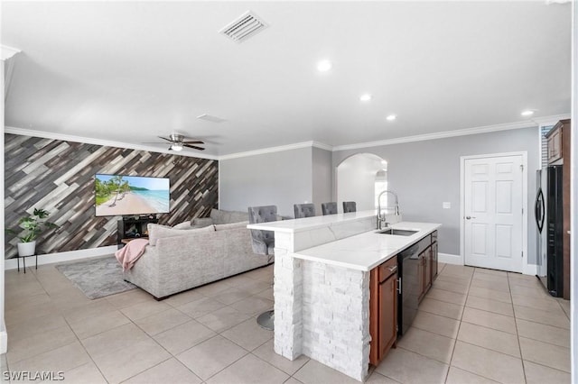 kitchen with sink, wooden walls, ceiling fan, black dishwasher, and an island with sink