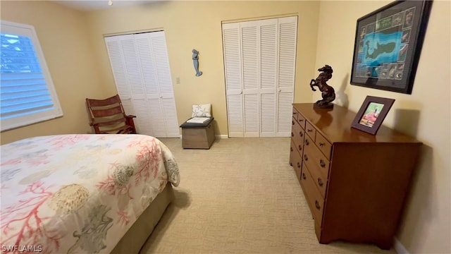 bedroom featuring multiple closets and light carpet