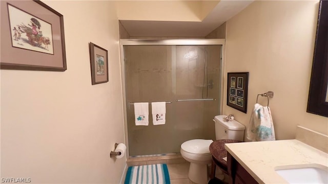 bathroom with vanity, toilet, a shower with shower door, and tile patterned flooring