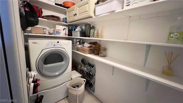 washroom with washer / clothes dryer, cabinets, and light tile patterned flooring