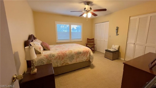 carpeted bedroom with two closets and ceiling fan