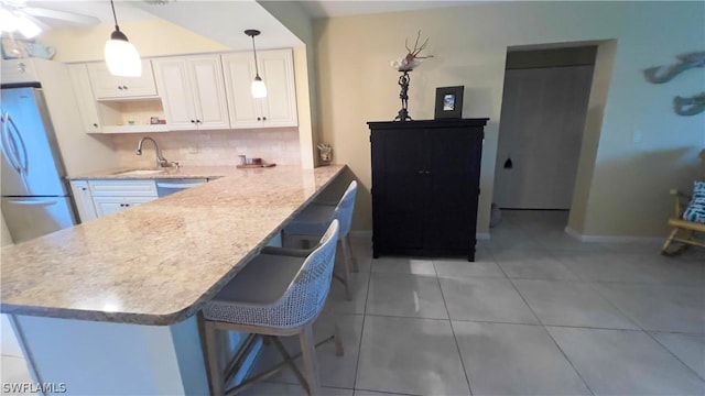 kitchen with sink, a breakfast bar area, white cabinetry, hanging light fixtures, and stainless steel appliances