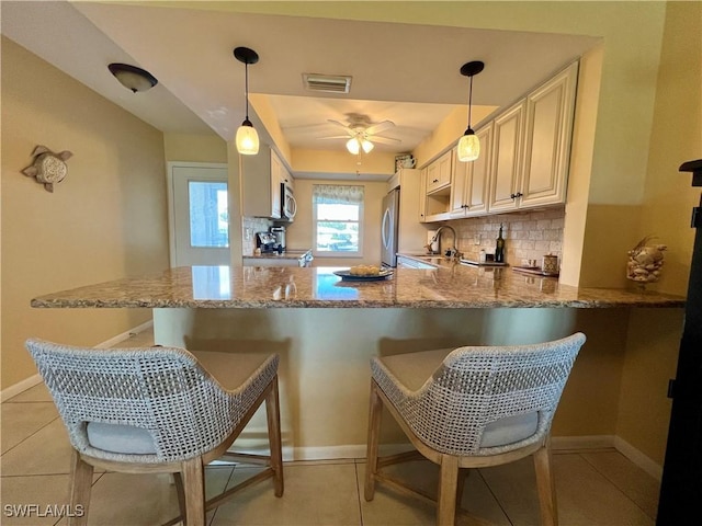 kitchen with decorative light fixtures, a kitchen breakfast bar, kitchen peninsula, and appliances with stainless steel finishes