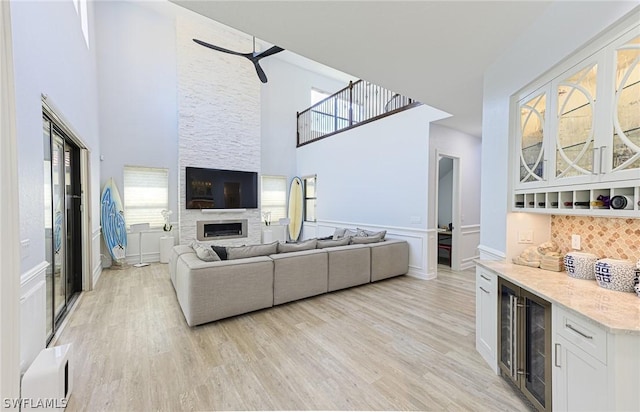 living room with a fireplace, a high ceiling, light hardwood / wood-style flooring, and a wealth of natural light