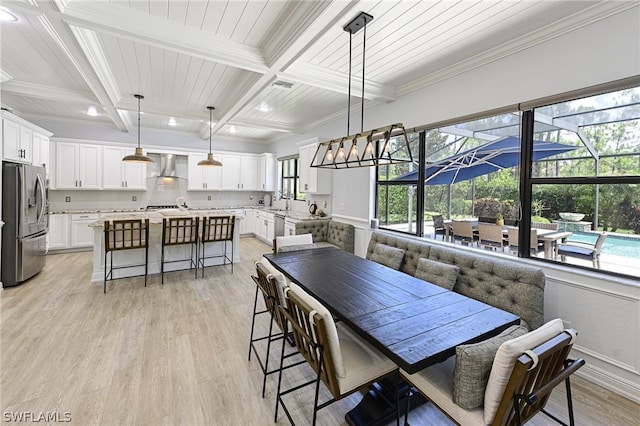 dining area featuring beamed ceiling, light wood-type flooring, and ornamental molding