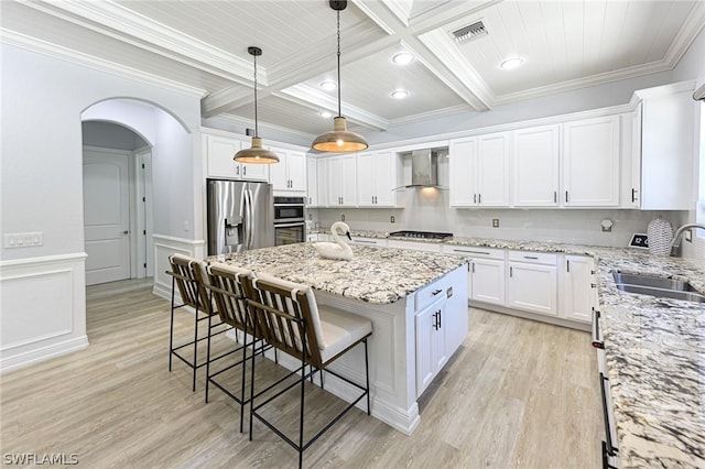 kitchen with white cabinetry, sink, wall chimney exhaust hood, a kitchen island, and appliances with stainless steel finishes