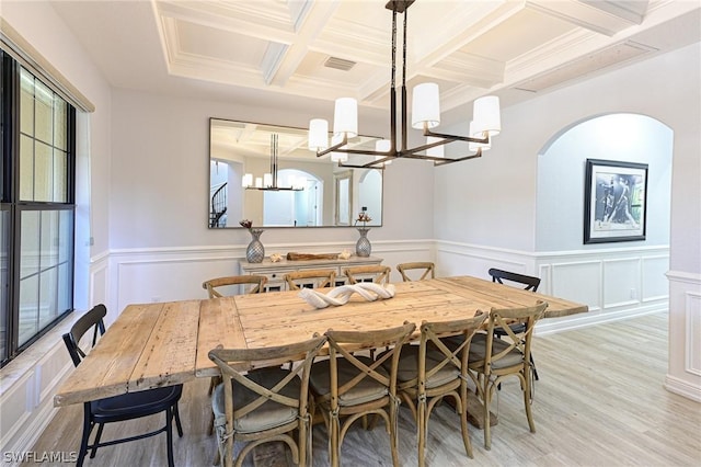 dining area with coffered ceiling, beamed ceiling, a chandelier, light wood-type flooring, and ornamental molding