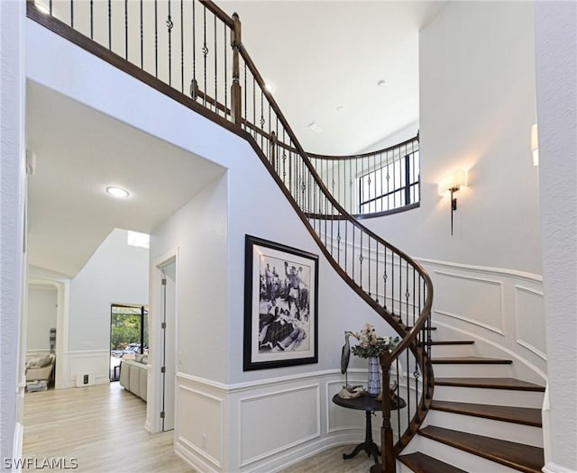 stairs with wood-type flooring and a high ceiling