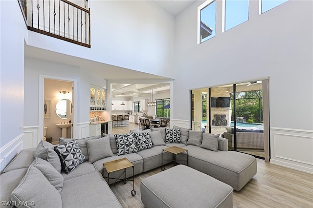 living room featuring a towering ceiling, a healthy amount of sunlight, and light hardwood / wood-style floors