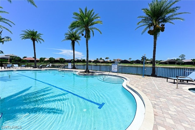 view of swimming pool featuring a water view and a patio