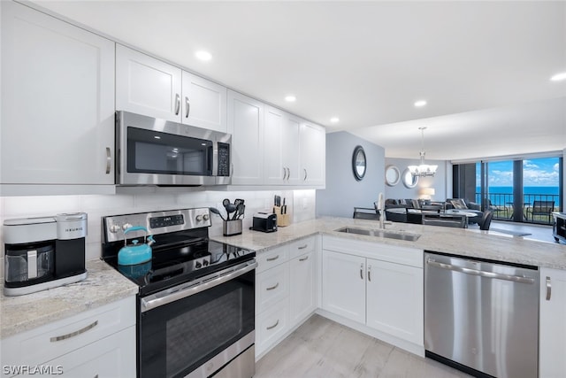 kitchen featuring light stone countertops, sink, a chandelier, white cabinets, and appliances with stainless steel finishes