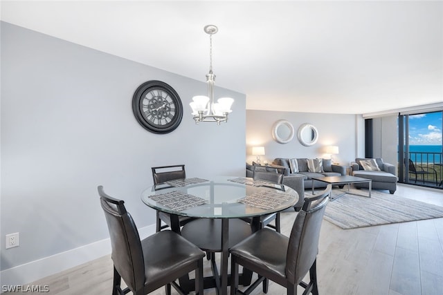 dining area with light wood-type flooring and a notable chandelier