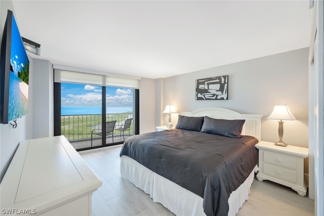 bedroom featuring access to exterior, floor to ceiling windows, a water view, and light hardwood / wood-style floors