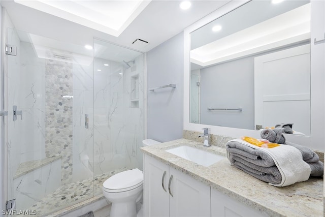 bathroom with vanity, toilet, a shower with door, and a tray ceiling