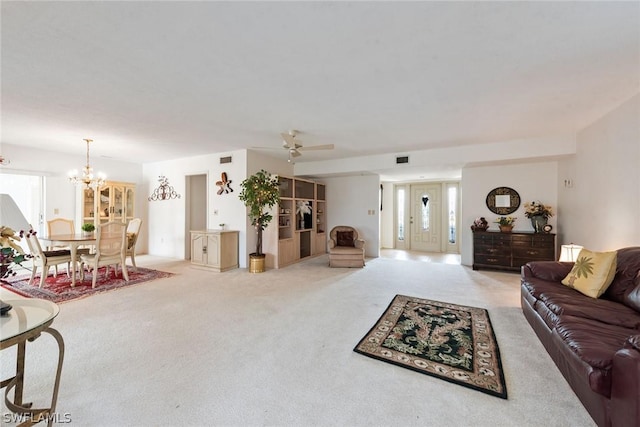 carpeted living room featuring ceiling fan with notable chandelier