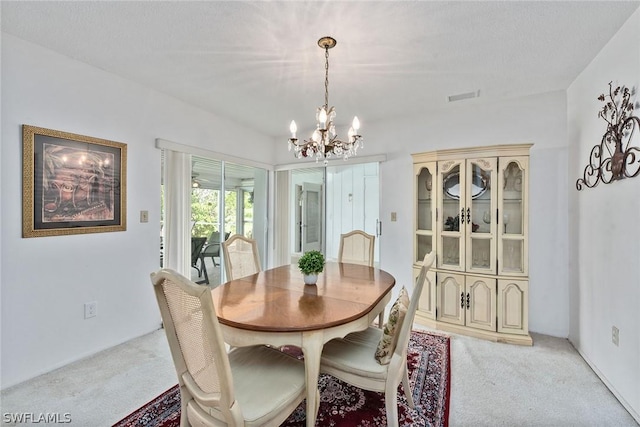 dining room with light colored carpet, a chandelier, and a textured ceiling