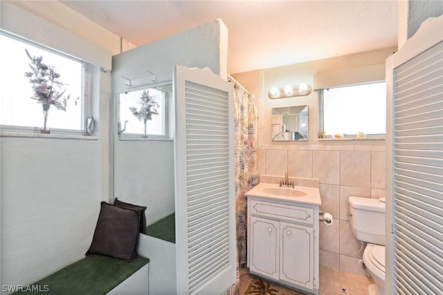 bathroom featuring toilet, vanity, tile walls, and tasteful backsplash