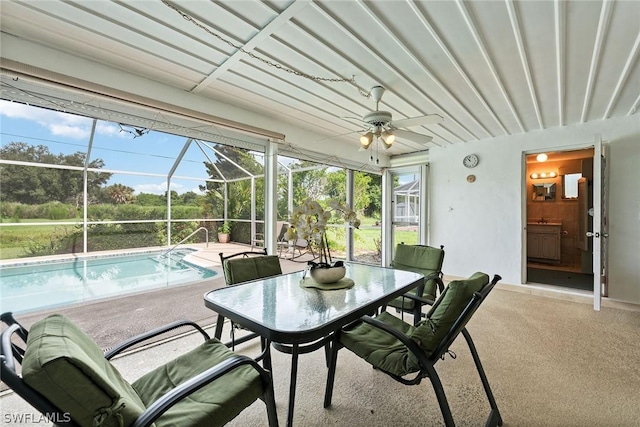 sunroom featuring ceiling fan, a pool, and a healthy amount of sunlight