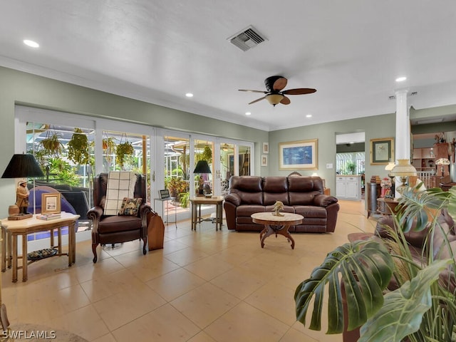 tiled living room featuring ornate columns, ceiling fan, and crown molding