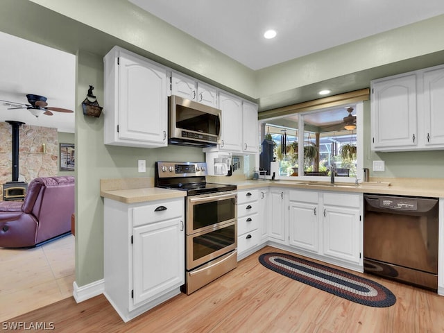 kitchen with white cabinets, ceiling fan, appliances with stainless steel finishes, and light hardwood / wood-style flooring